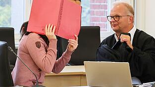 Die Angeklagte betritt den Gerichtssaal seit Monaten mit Fußfesseln und einem Aktendeckel vor dem Gesicht. Die Angeklagte betritt den Gerichtssaal seit Monaten mit Fußfesseln und einem Aktendeckel vor dem Gesicht.