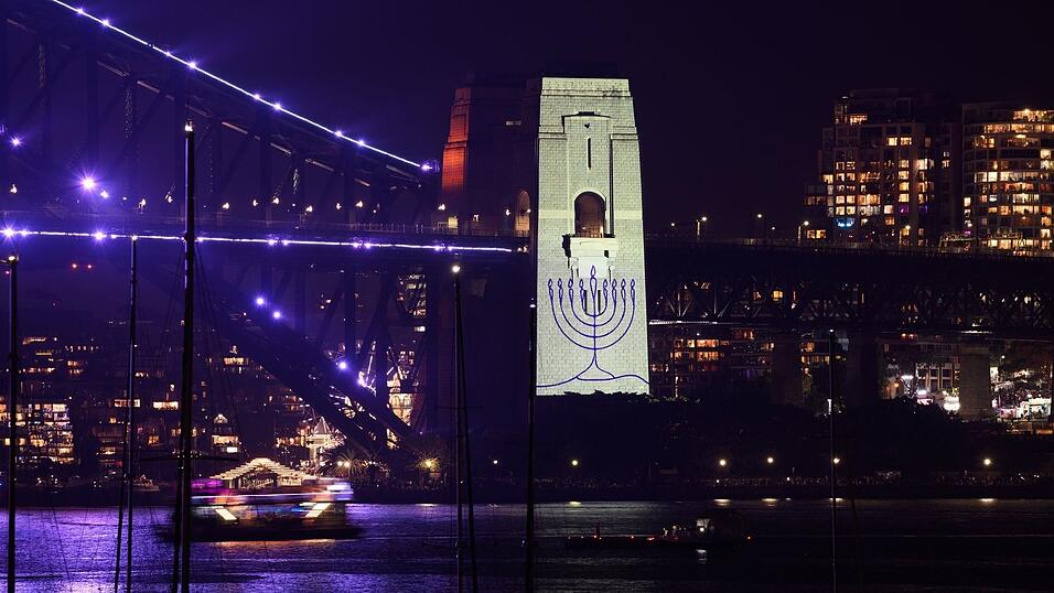 Während einer Schweigeminute wurde ein Chanukkaleuchter auf einen Pfeiler der Sydney Harbour Bridge projiziert. Während einer Schweigeminute wurde ein Chanukkaleuchter auf einen Pfeiler der Sydney Harbour Bridge projiziert.