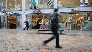 Passanten gehen durch eine Fußgängerzone. Passanten gehen durch eine Fußgängerzone.