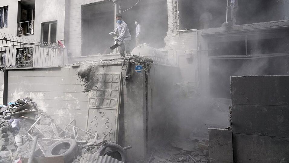 Freiwillige r&auml;umen in Teheran in den Tr&uuml;mmer eines Wohnhauses, das besch&auml;digt wurde, als eine nahe gelegene Polizeistation bei einem amerikanisch-israelischen Angriff getroffen wurde, auf.