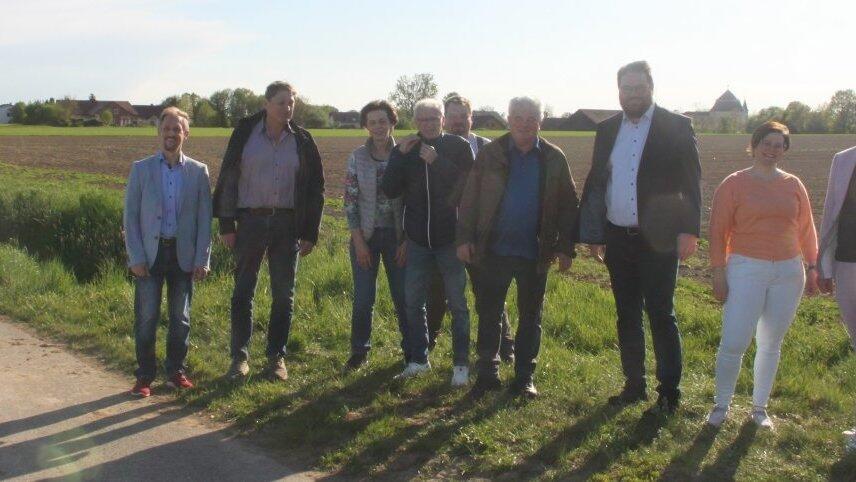Die Teilnehmer des Treffens mit MdL Tobias Beck und Kirchroths Bürgermeister Matthias Fischer an dem möglichen Standort für ein Umspannwerk in der Flur bei Niederachdorf. Im Hintergrund ist das Dach der Wallfahrtskirche in Niederachdorf erkennbar.