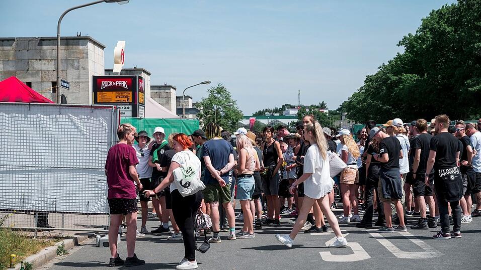 Besucherinnen und Besucher warten vor Beginn des Open-Air-Festivals Rock im Park auf den Einlass.