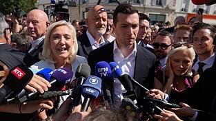 Marine Le Pen steht im Mittelpunkt des Interesses, Jordan Bardella genervt daneben: Der bisher so erfolgreiche junge Parteivorsitzende der Rechtsextremen in Frankreich muss wieder in die zweite Reihe zur&uuml;ck. (Archiv)
