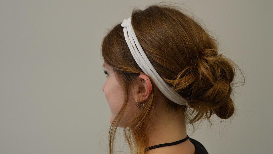 Lege das Haarband unter den wuscheligen Dutt und befestige es über dem Scheitel. Lege das Haarband unter den wuscheligen Dutt und befestige es über dem Scheitel.