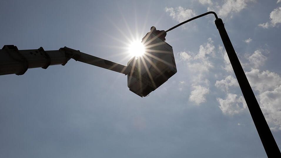 Ein Elektromonteur montiert in Halle eine neue LED-Leuchte für die Straßenbeleuchtung. Ein Elektromonteur montiert in Halle eine neue LED-Leuchte für die Straßenbeleuchtung.