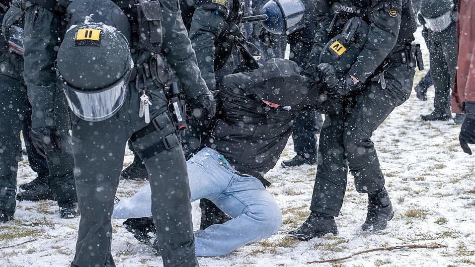Polizisten bringen am Rande einer Demonstration eine Person zu Boden.
