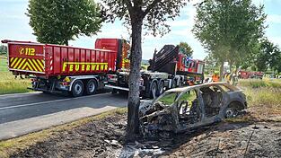 Das ausgebrannte Unfallwrack eines Autos steht an einem Baum. Eine junge Fahrerin ist in Gro&szlig; Kreutz bei Potsdam mit ihrem E-Auto gegen einen Baum geprallt und darin verbrannt.