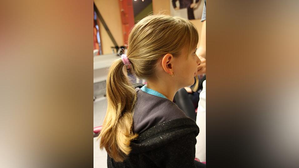 1. Leonie bindet ihre Haare zun&auml;chst mit einem Gummi zu einem Pferdeschwanz auf mittlerer H&ouml;he zusammen. An der Seitenpartie l&auml;sst sie eine dickere Str&auml;hne aus, diese wird sp&auml;ter gekordelt.