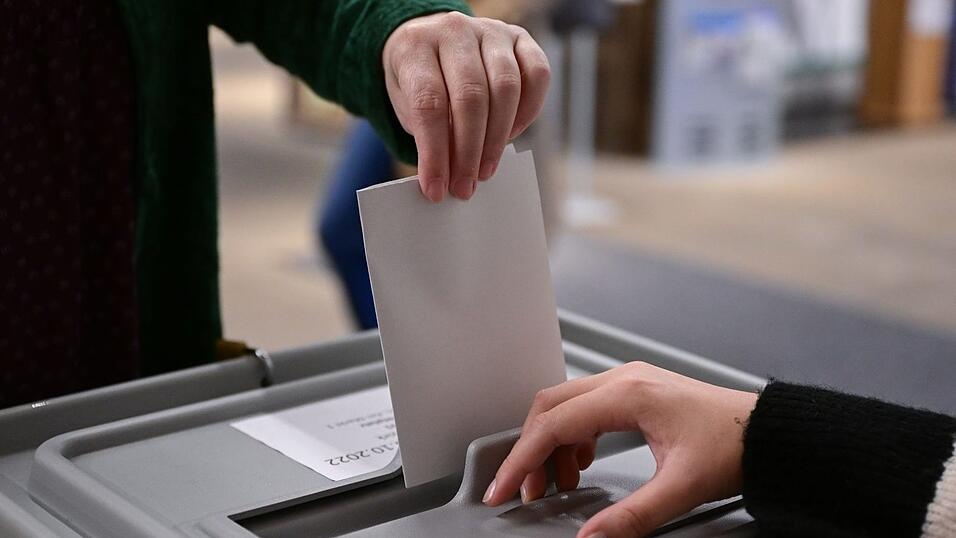 Ein Wähler steckt bei einer Wahl seinen Wahlzettel in eine Urne. Ein Wähler steckt bei einer Wahl seinen Wahlzettel in eine Urne.