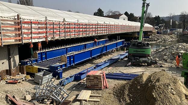 Die neue Br&uuml;cke &uuml;ber die Kleine Isar wird in den n&auml;chsten Monaten fertig. Dann zieht die Baustelle 500 Meter weiter: Die Behelfsumfahrung wird &uuml;ber der Gro&szlig;en Isar aufgebaut, damit die dortige Br&uuml;cke abgerissen werden kann.