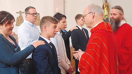 Generalvikar Josef Ederer besiegelte mit Chrisam die Firmung bei Jakob Vaitl mit seiner Patin Lea Eberhardt. Assistiert wurde ihm von Diakon Frater Symeon-Maria Fiegler OSB (r.).