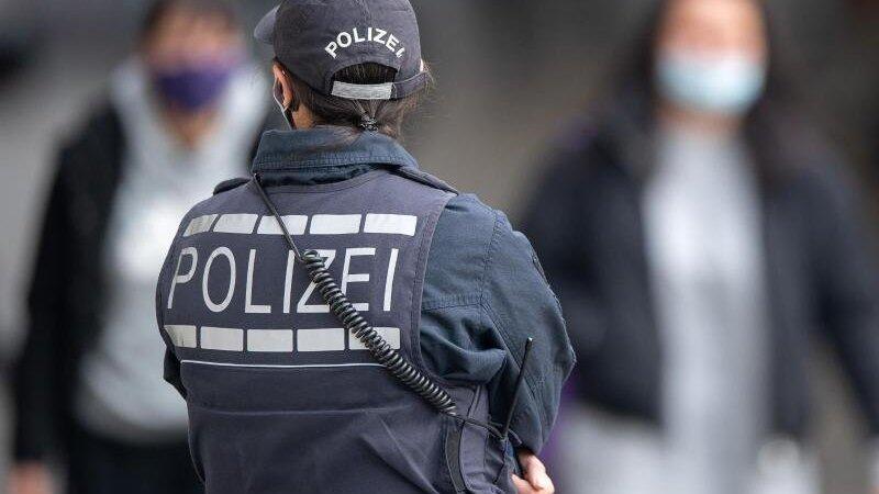 Eine Polizistin Blickt zu Passanten mit Masken. Eine Polizistin Blickt zu Passanten mit Masken.