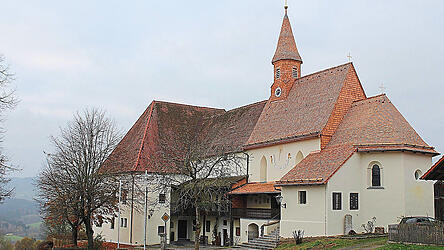 Das kirchliche Kleinod zeigt sich im neuen Kleid. Der gesamte Komplex besteht aus dem ehemaligen Schloss (links), der ehemaligen Gaststätte (Mitte), und der Kirche (rechts), deren Dachschindeln optisch auffallen.
