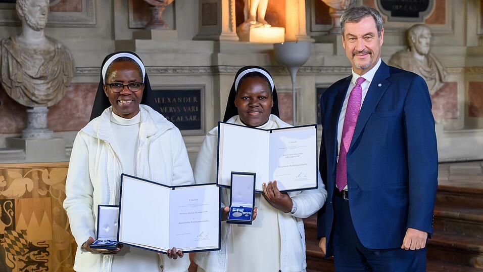 Ministerpr&auml;sident Markus S&ouml;der &uuml;berreicht die Rettungsmedaille an die Strahlfelder Schwestern Stembile und Alexia (links).