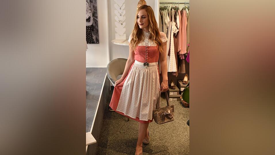 Auch dieses Dirndl trägt man am besten mit einer hochgeschlossenen Bluse. Die passenden Schuhe und eine Tasche runden den Look ab.