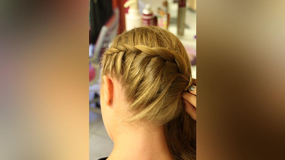 1. Hannah zieht einen Seitenscheitel und beginnt auf der Seite, auf der weniger Haare sind, schr&auml;g nach hinten (bis zur Mitte des Hinterkopfes) zu flechten. Dazu nimmt sie eine Haarpartie und teilt sie in drei Teile. Jeweils von unten nimmt sie immer wieder eine Str&auml;hne hinzu.