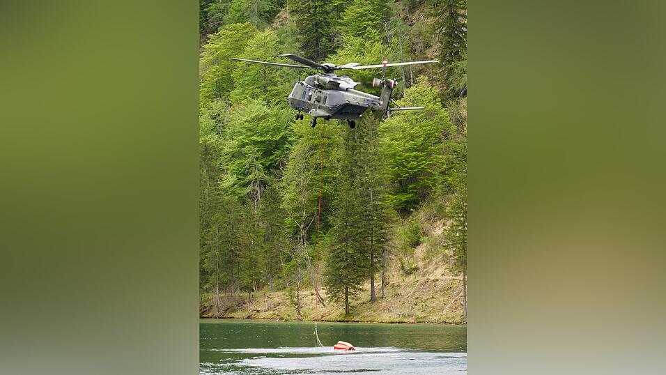Ein Hubschrauber f&uuml;llt einen L&ouml;schwasserbeh&auml;lter.