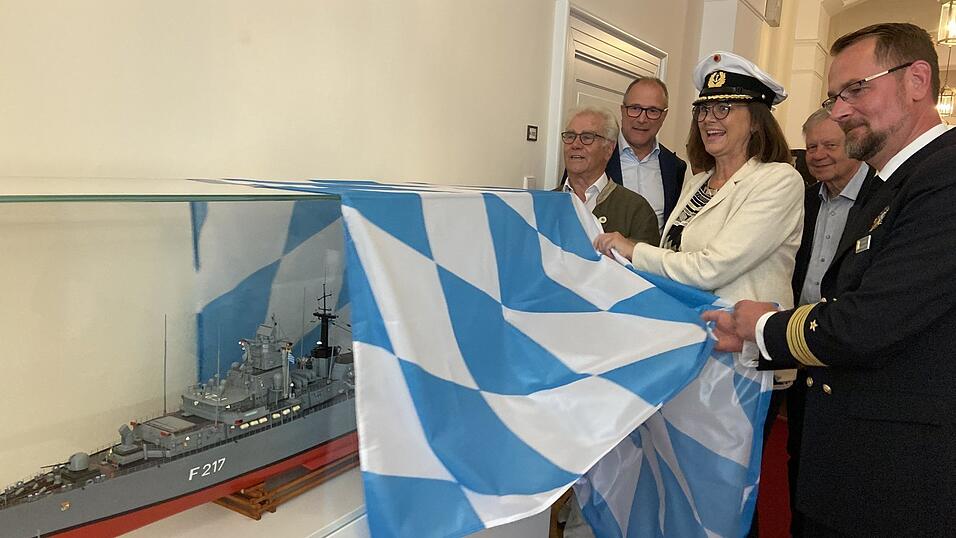 Landtagspr&auml;sidentin Ilse Aigner und Fregattenkapit&auml;n Dennis Fauerbach (r.) enth&uuml;llen das Modell im Beisein von Rudolf Peterke vom Freundeskreis Fregatte Bayern (l.).