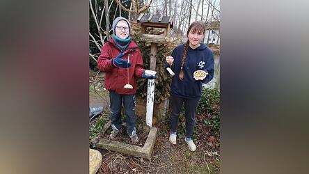 Benedikt und Milena bringen die Leckereien f&uuml;r die V&ouml;gel am Futterh&auml;uschen an.