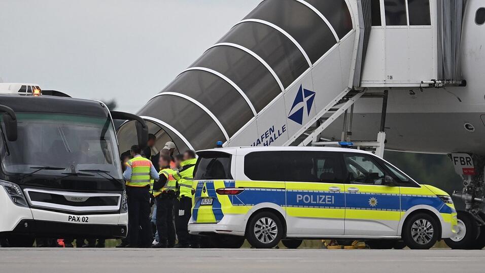 Menschen steigen am Flughafen Leipzig/Halle in ein Flugzeug. Am Fuß der Treppe stehen Polizeibeamte und ein Poliezifahrzeug. Ende Juli ist ein Abschiebeflug von Deutschland aus gestartet. Menschen steigen am Flughafen Leipzig/Halle in ein Flugzeug. Am Fuß der Treppe stehen Polizeibeamte und ein Poliezifahrzeug. Ende Juli ist ein Abschiebeflug von Deutschland aus gestartet.