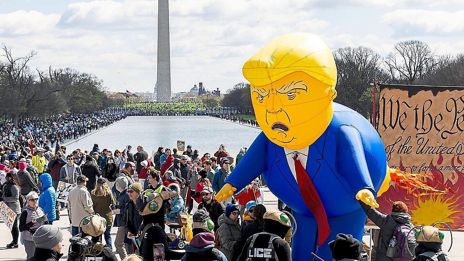 Ein aufblasbarer Ballon, der den US-Pr&auml;sidenten Trump darstellen soll, ragt &uuml;ber Menschen. Die Szene zeigt den Marsch von der Memorial Bridge bis zum Washington Monument.