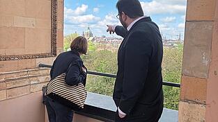 Tobias Beck zeigt seiner Nachr&uuml;ckerin Johanna Schramm vom Balkon des Landtages aus, wo was in M&uuml;nchen zu finden ist.