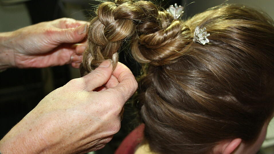 Den Zopf auflockern und um den Dutt legen. Den Zopf auflockern und um den Dutt legen.