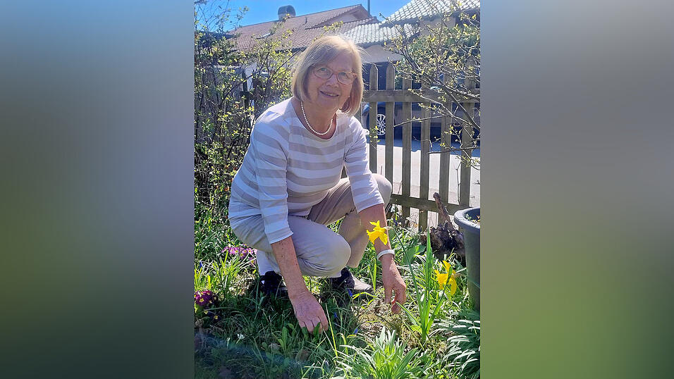 Brigitte R&ouml;ll in ihrem Naturgarten, in dem neben lila Primeln und Traubenhyazinthen leuchtend-gelbe Narzissen mit der Fr&uuml;hlingssonne um die Wette strahlen.