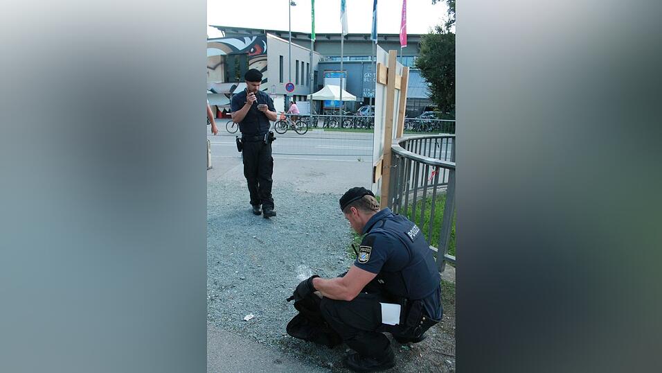 W&auml;hrend sein Kollege den Rucksack untersucht, &uuml;berpr&uuml;ft der Polizist die Personalien zweier M&auml;nner.