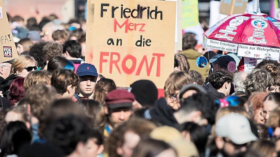 Spr&uuml;che wie &bdquo;Friedrich Merz an die Front&ldquo; sind auf Schildern der Demonstranten auf dem Potsdamer Platz in Berlin zu lesen.