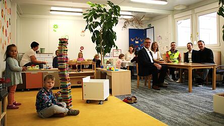 Die Kinder fühlen sich pudelwohl in ihrem neuen Gruppenraum, und auch Bürgermeister Hans Schmalhofer (hinten, v. l.), Kindergartenleiterin Claudia Weiß, Florian Loibl vom technischen Bauamt, Geschäftsleiter Sandro Pfeiffer und Arno Baumgartner vom Planungsbüro nahmen versuchsweise Platz.