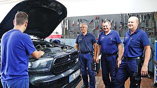 Betriebsleiter Johann Engl (rechts) mit seinen Kollegen und einem der sechs Mitarbeiter, Daniel (links), der unbedingt in der Kfz-Werkstatt arbeiten wollte und hier dazulernt, aber auch Wissen weitergibt, wie er sagt.