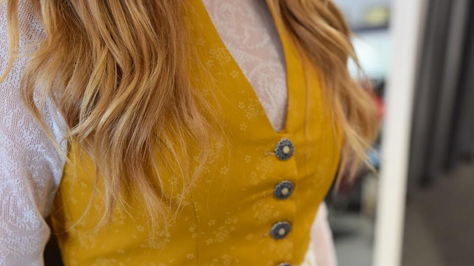 Das Vintage-Dirndl hat einen V-Ausschnitt. Die langärmelige Spitzenbluse ist hochgeschlossen.