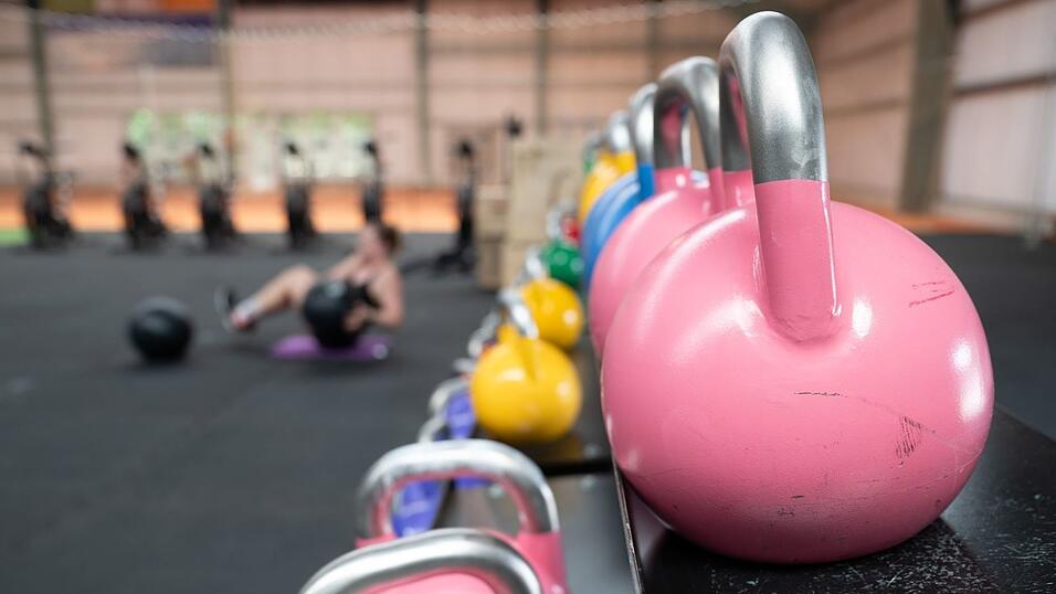 Eine Frau &uuml;bt an einer Hantelbank.