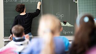 Eine Lehrerin schreibt in einer Schule an die Tafel.