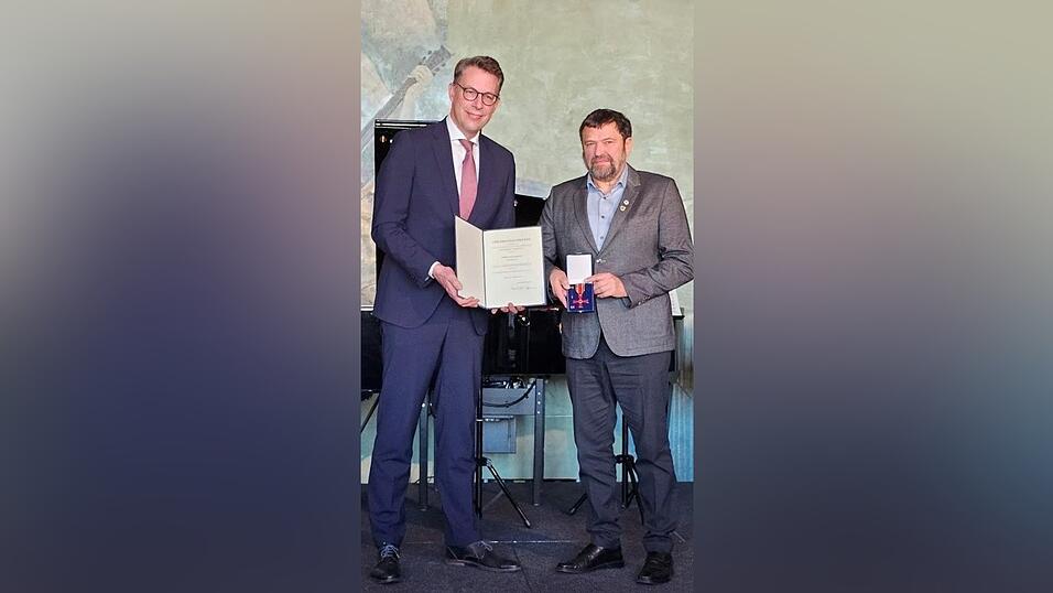 Der gro&szlig;e Moment: Wissenschafts- und Kunstminister Markus Blume &uuml;berreicht Max Schmatz das Bundesverdienstkreuz.