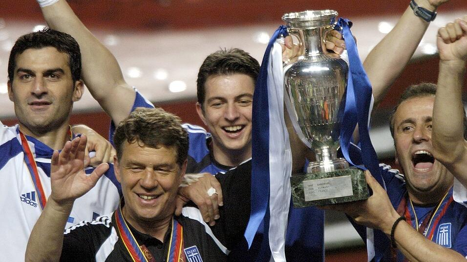 Lissabon, 4. Juli 2004 | Griechenlands deutscher Trainer Otto Rehhagel (vorn l.) und sein griechischer Assistent und Dolmetscher Ioannis Topalidis (r.) jubeln mit dem gewonnenen EM-Pokal und ihren Spielern. Im Endspiel schl&auml;gt Griechenland im Estadio da Luz Gastgeber Portugal mit 1:0.